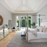 Master bedroom with vaulted decorative ceiling and a view of the pool area through French doors in the Harrison house plan