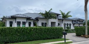 View of the front elevation of a 1-story 3,733 sf house with stucco finish and metal roof